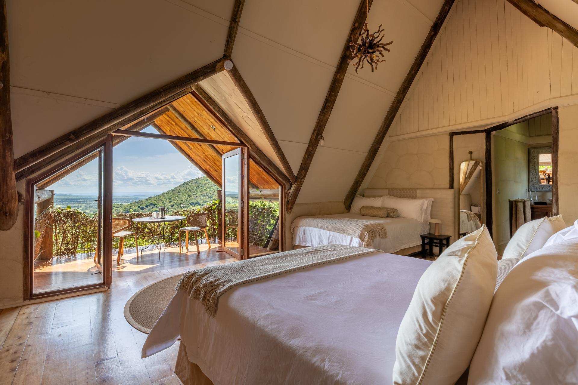 Twin beds under a high apex ceiling with cream mosquito nets.