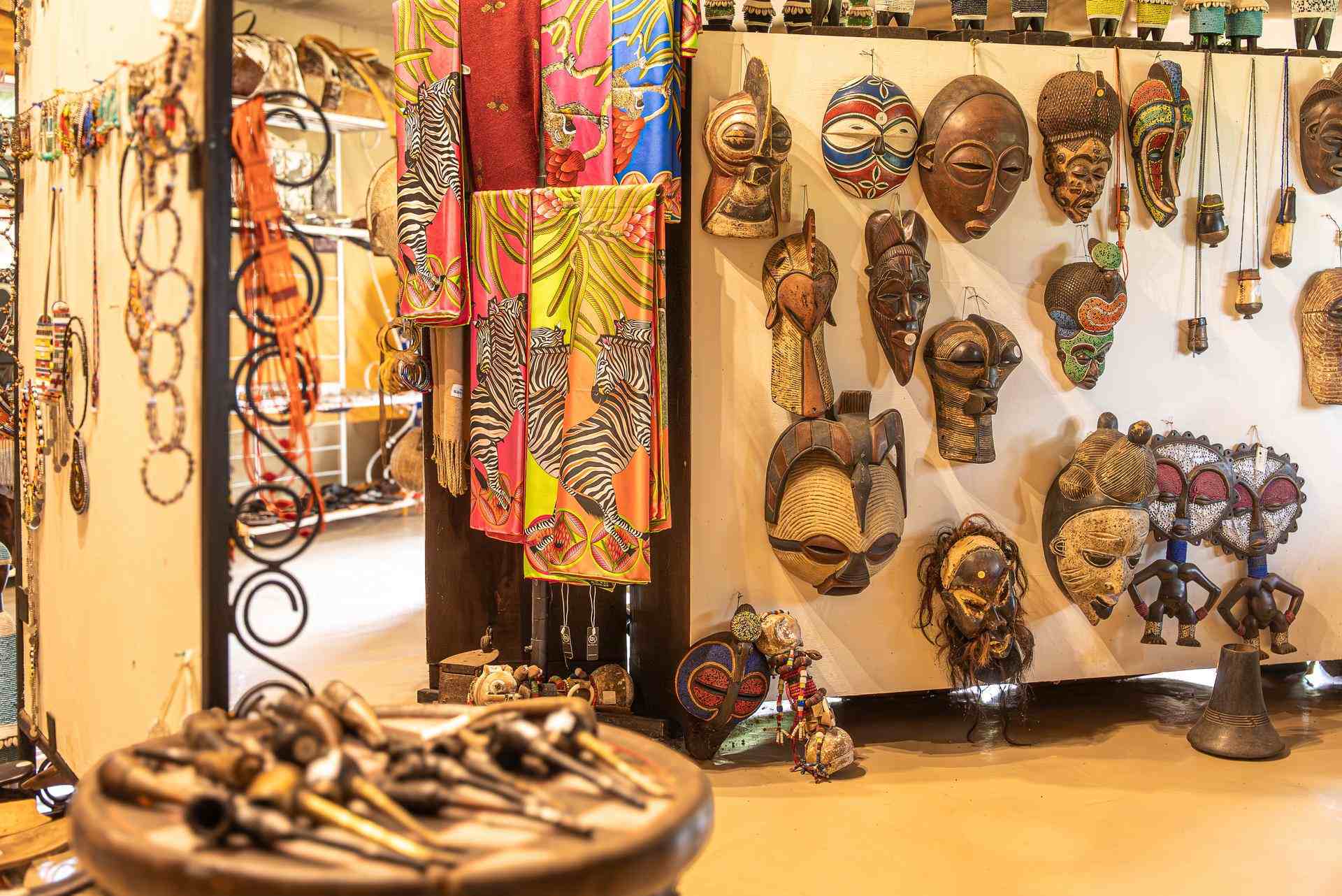 The Dapper Flapper Boutique Interior of The Dapper Flapper Boutique at Cottar’s 1920s Camp showcasing African masks, handmade jewelry, colorful scarves, and artisan crafts from Kenyan designers.