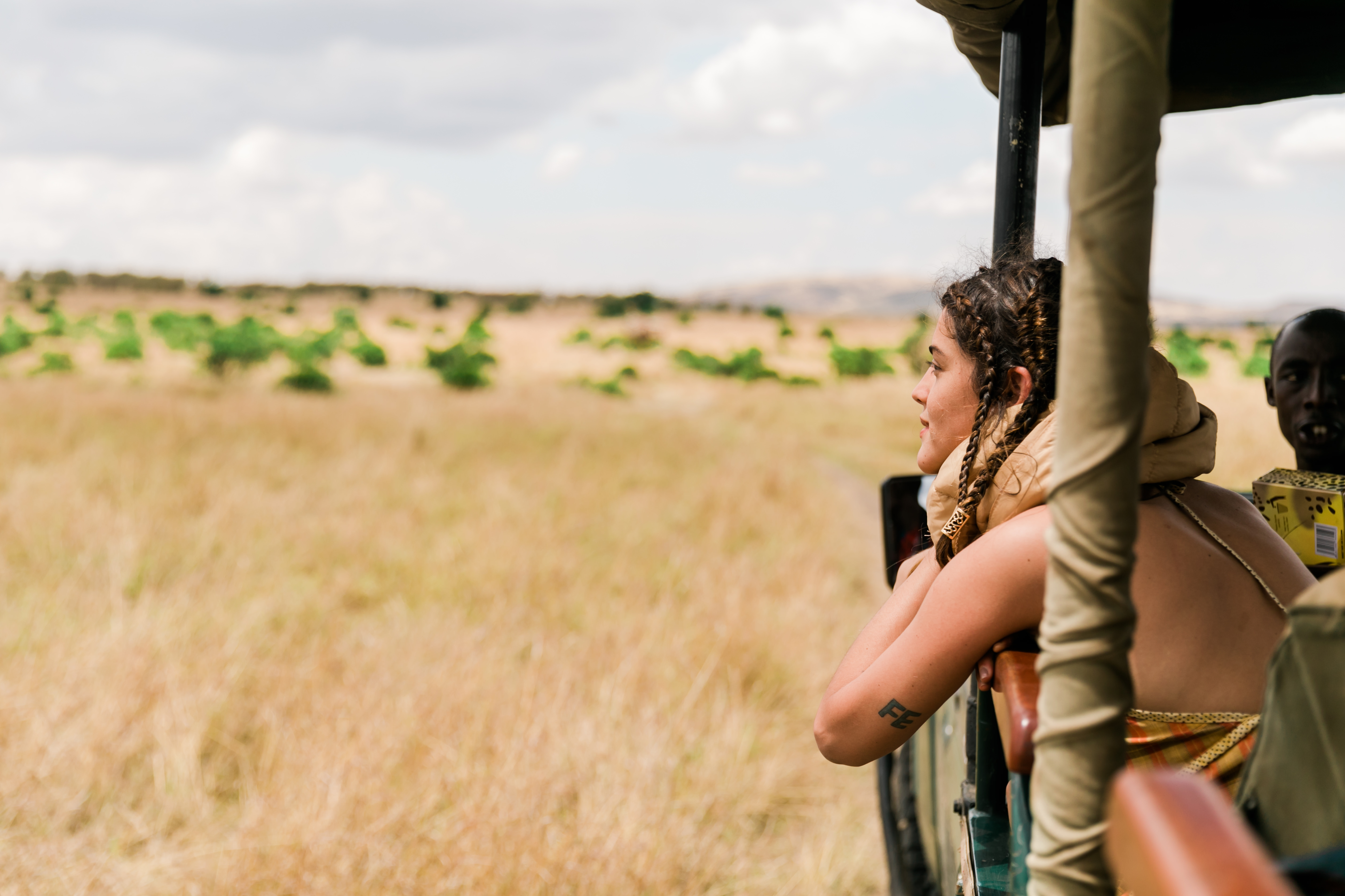 Guest enjoying panoramic views from an open safari vehicle during a game drive in the Maasai Mara.