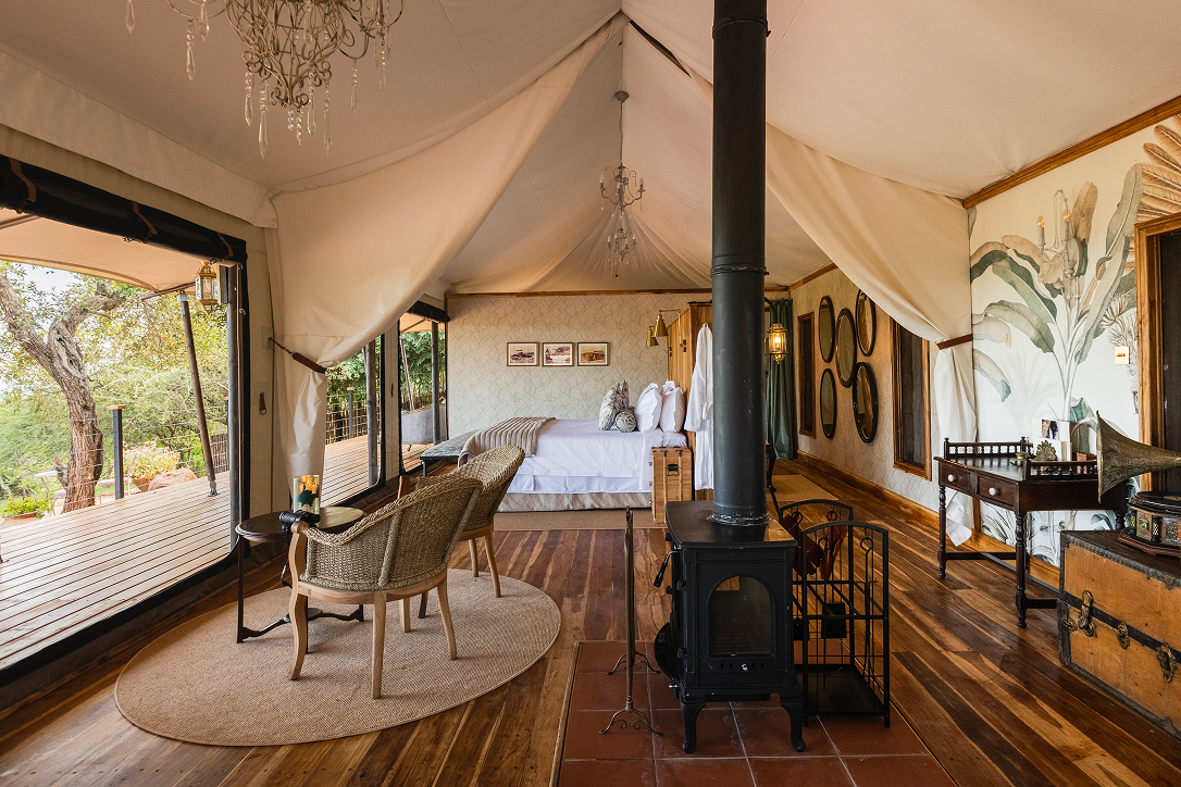 Elegant bedroom inside Cottar’s Bush Villa with a wood-burning stove and private veranda.