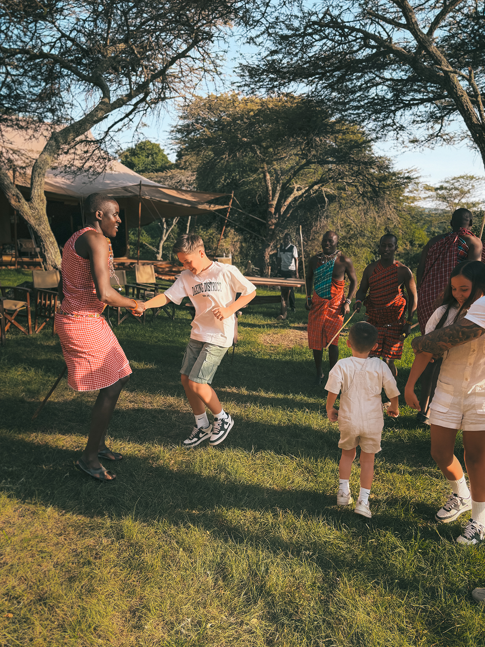 Children dancing with Maasai guides during a family safari at Cottar’s 1920s Camp.
