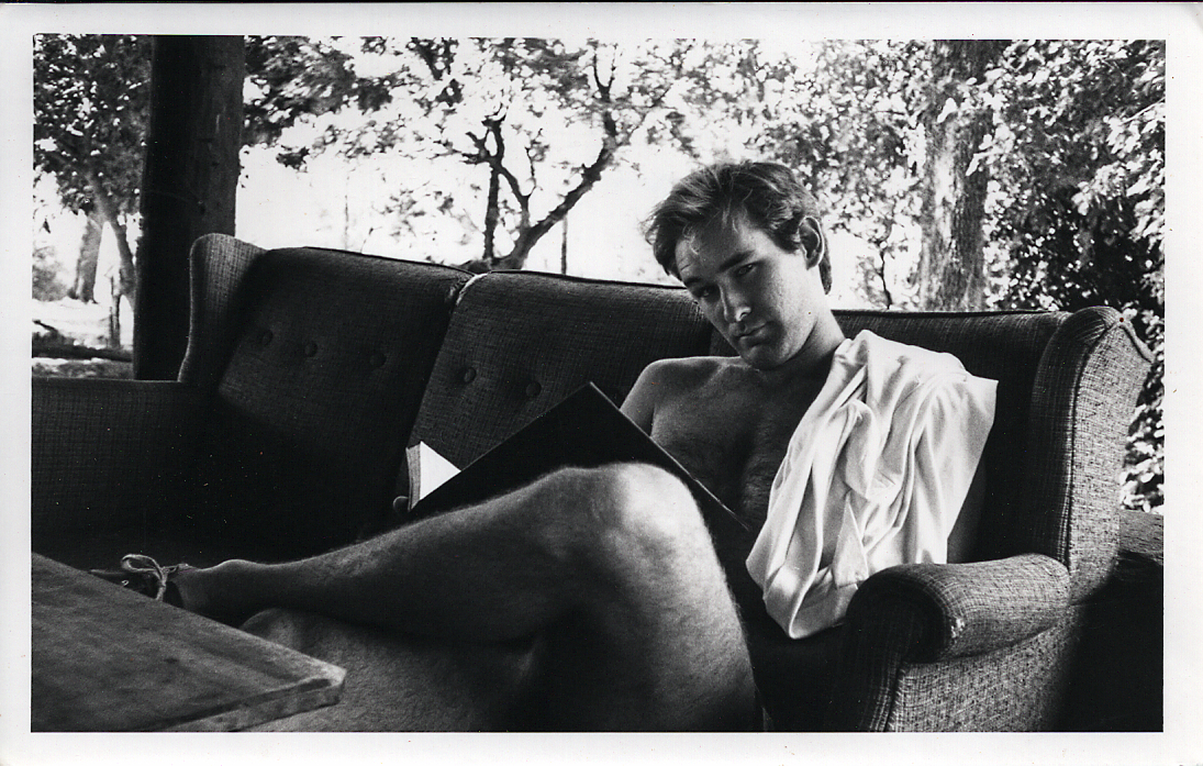 Black-and-white photograph of a young Calvin Cottar reading on the veranda of the family safari camp.