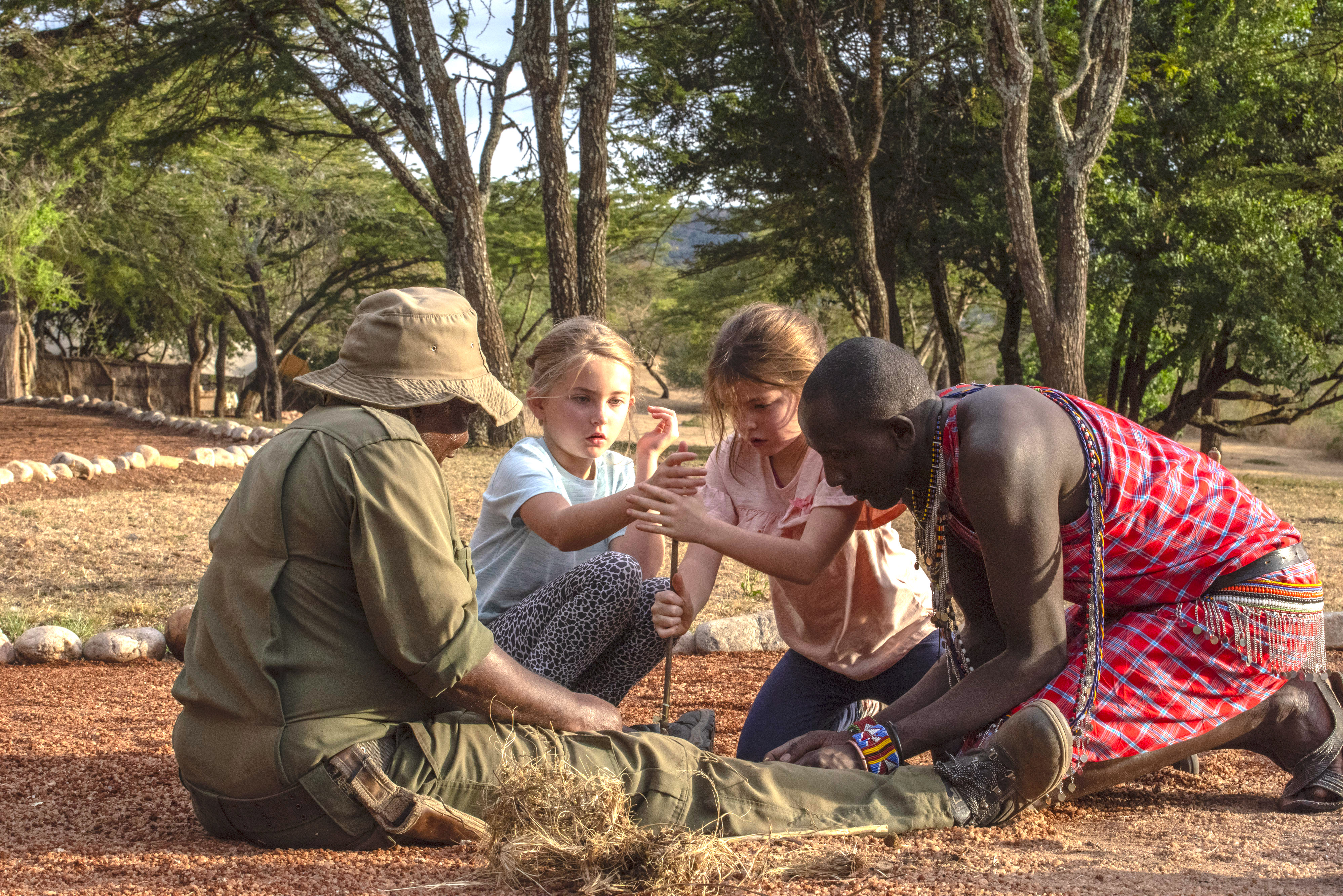Children learning traditional Maasai fire-making skills with local guides at Cottar’s 1920s Camp.