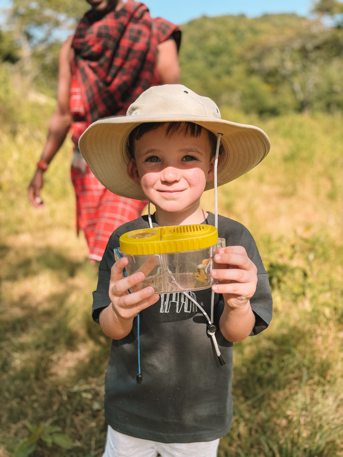 Young safari guest holding an insect observation container during a children’s bush exploration activity.