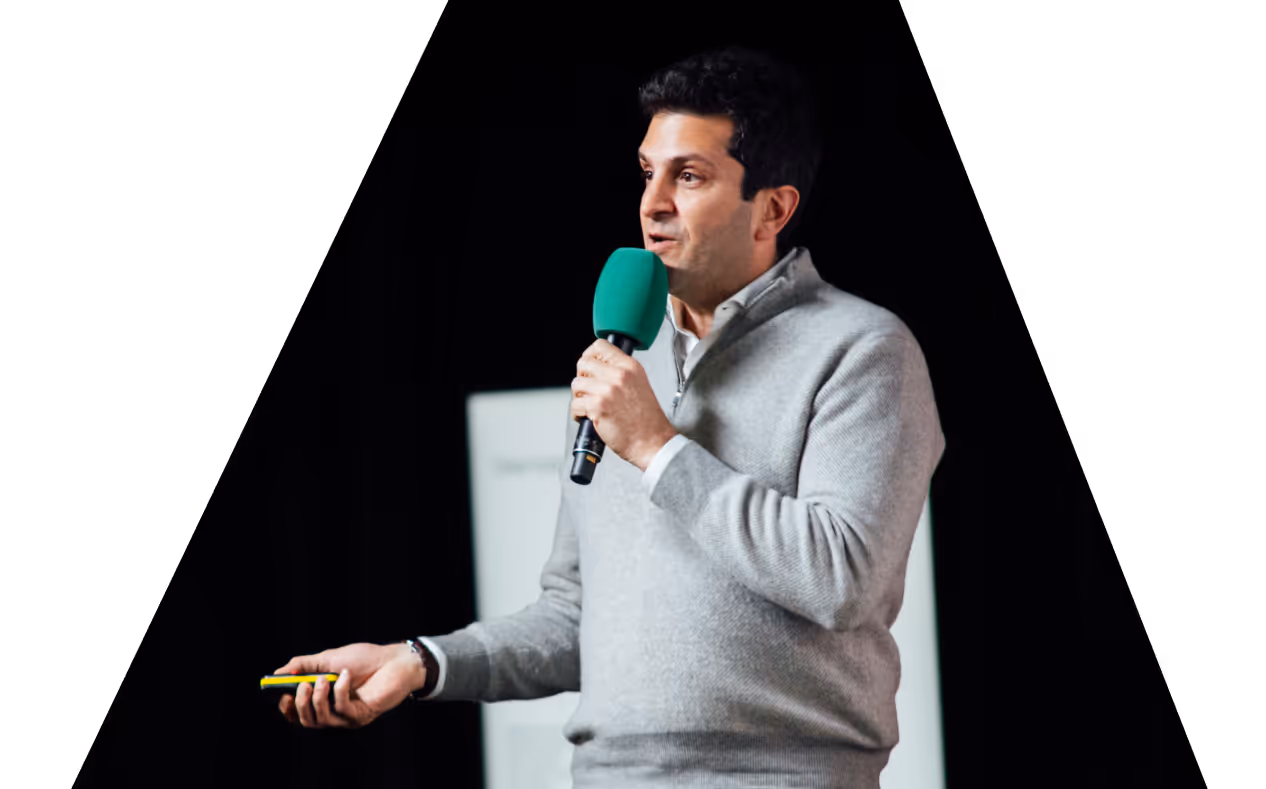 A presenter speaks into a microphone during a talk or pitch event.