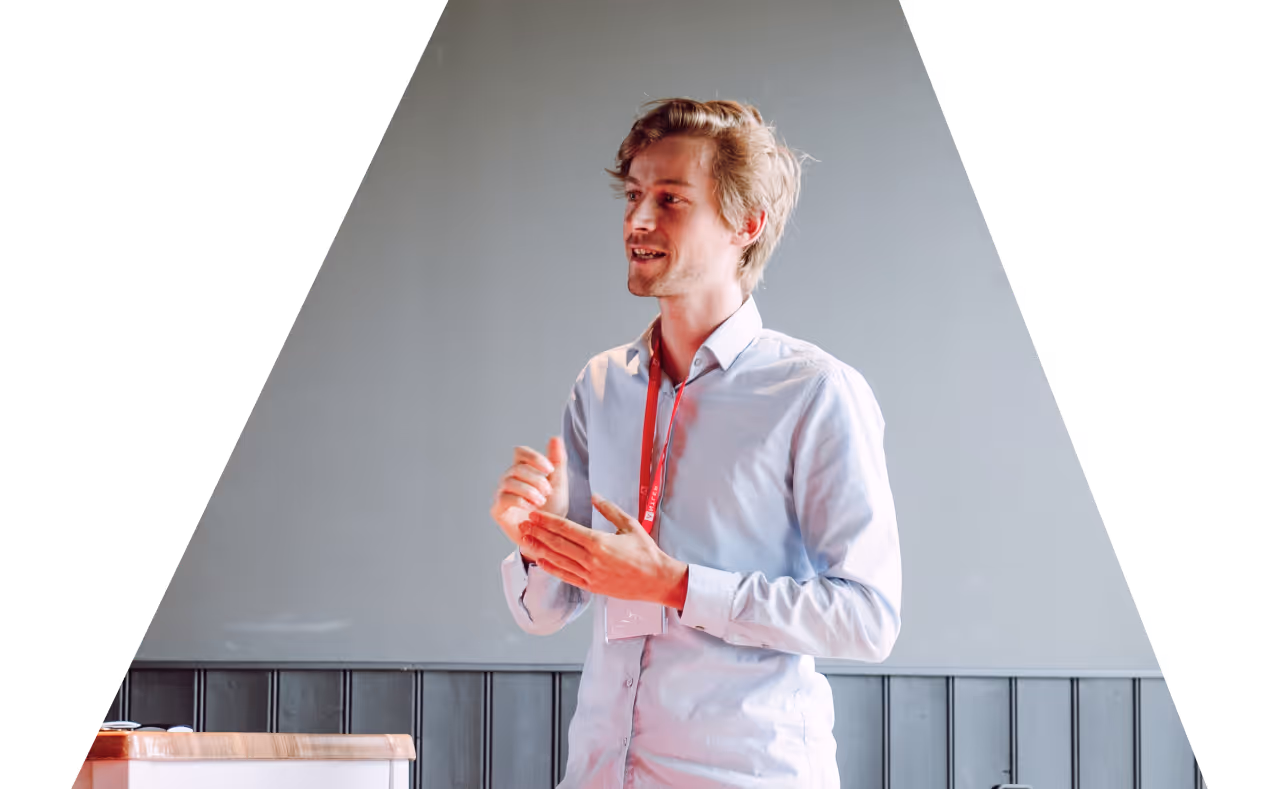 A man with glasses smiles while engaged in a conversation at an event.