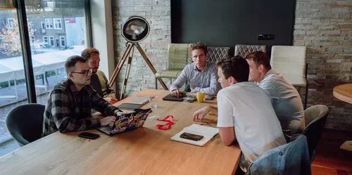 Founders and team members collaborating around a meeting table in a modern office setting.