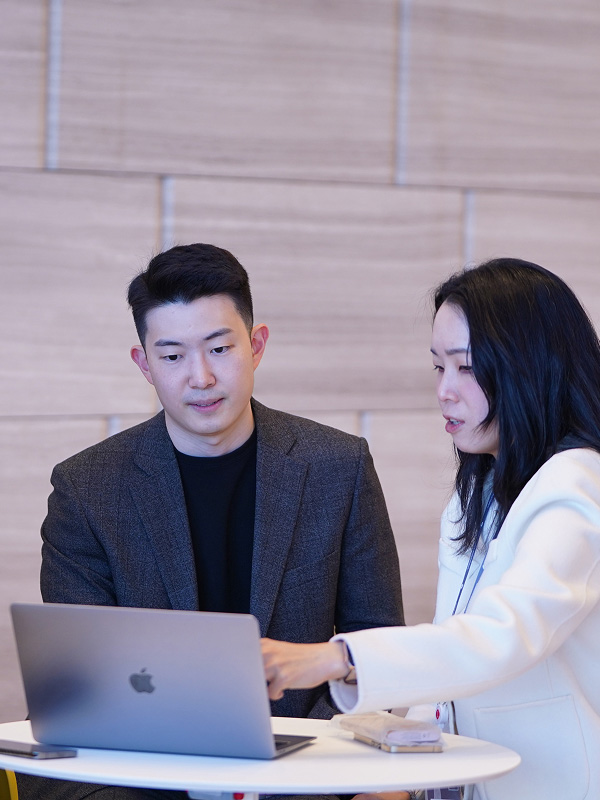 한 남자와 한 여자가 노트북 화면을 보고 있다.