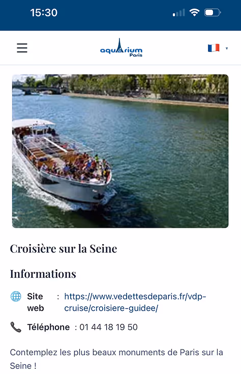 A boat traveling down a river next to a forest.