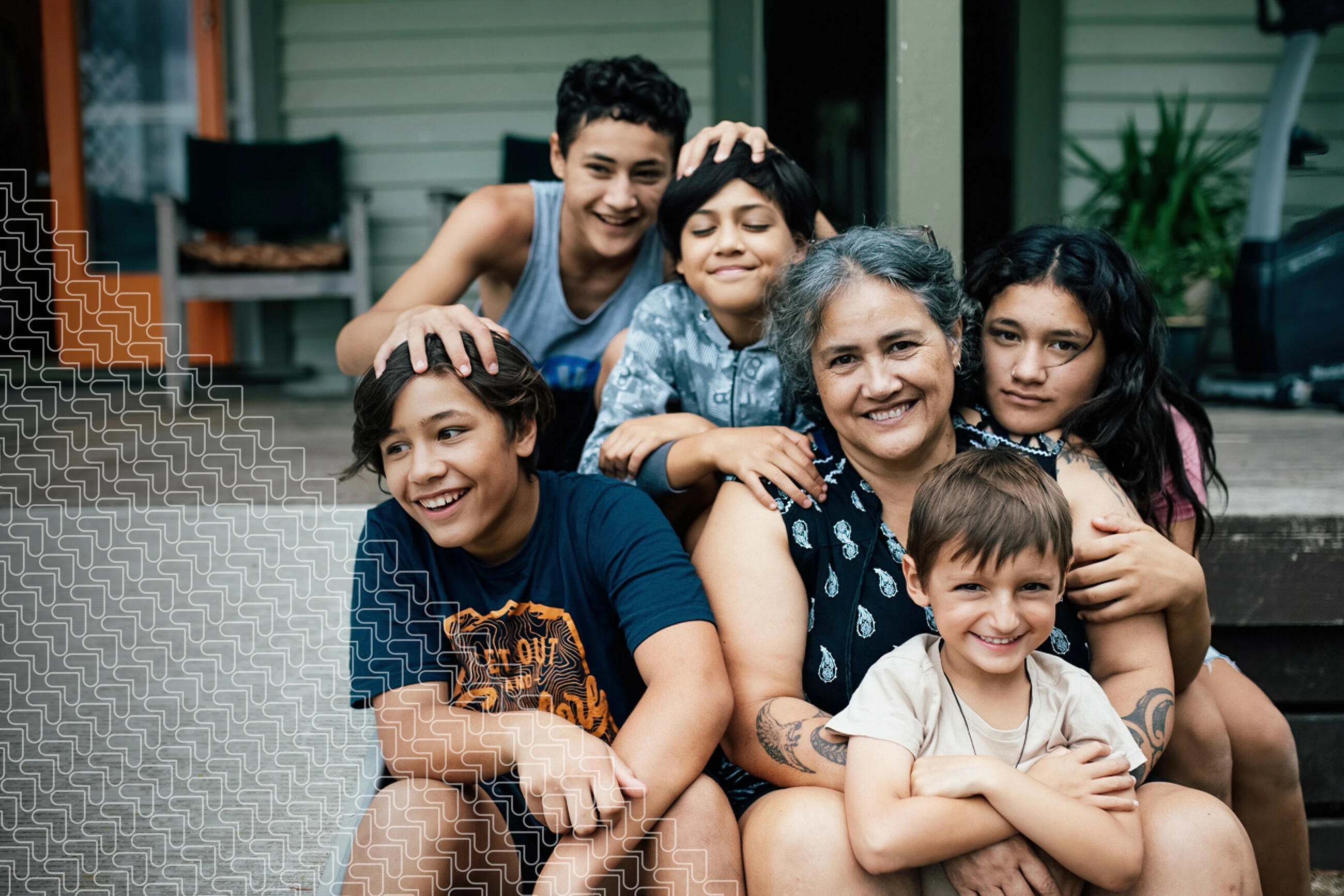 large family on porch of home, hugging each other and smiling -grandma and children