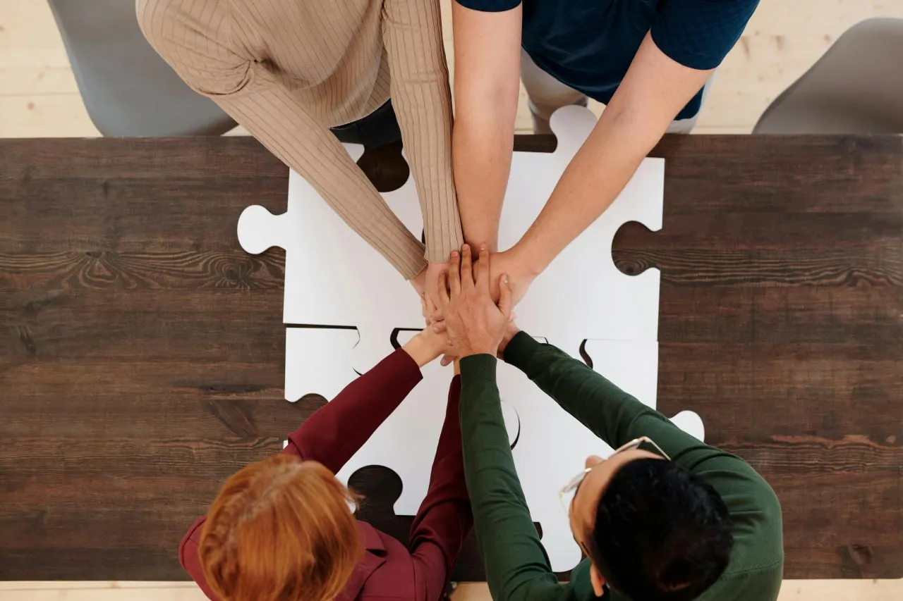 Mains réunies au-dessus de pièces de puzzle, symbole de collaboration en équipe