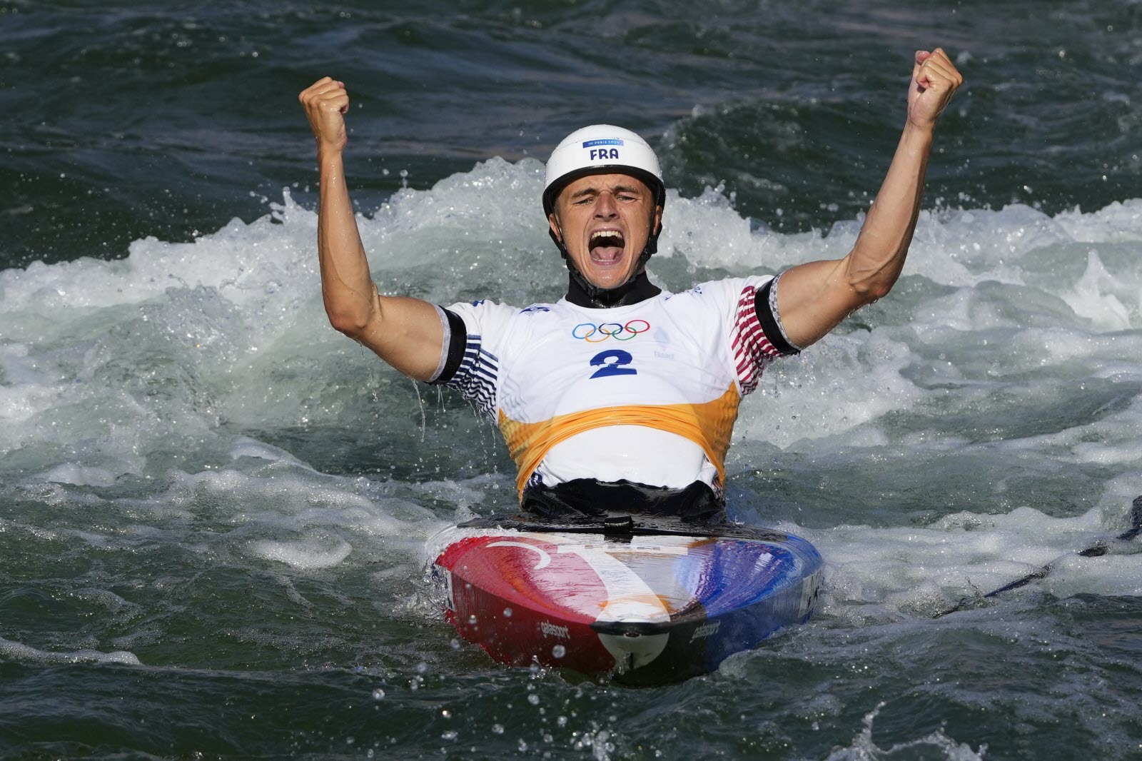 athlète de kayak slalom célébrant dans l’eau avec les bras levés pendant une compétition