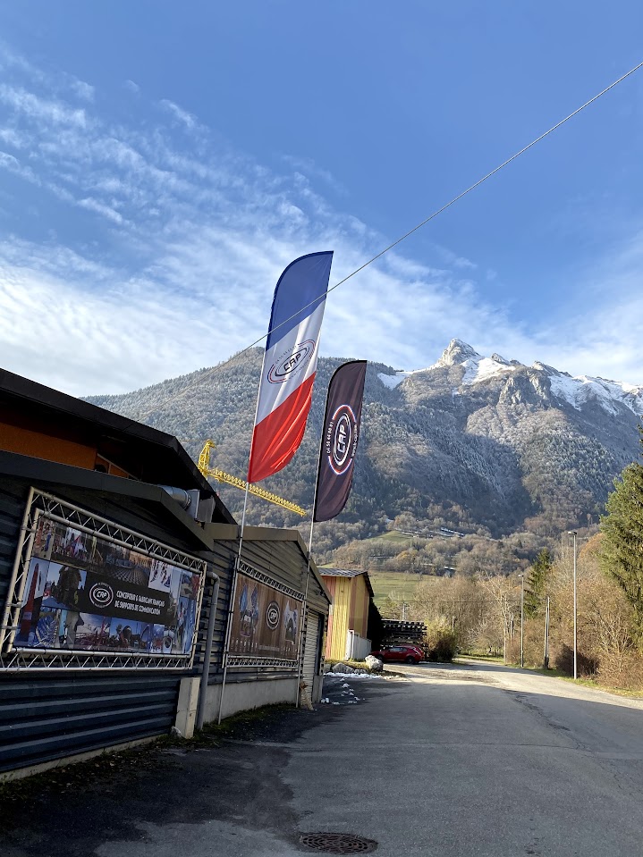 drapeaux publicitaires installés devant un bâtiment sur fond de montagnes enneigées, utilisés pour la communication lors d’événements