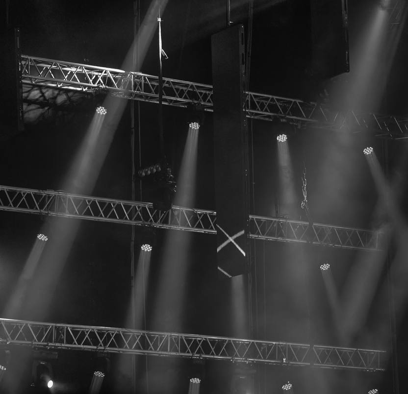 Concert stage lights shining through haze during live music event