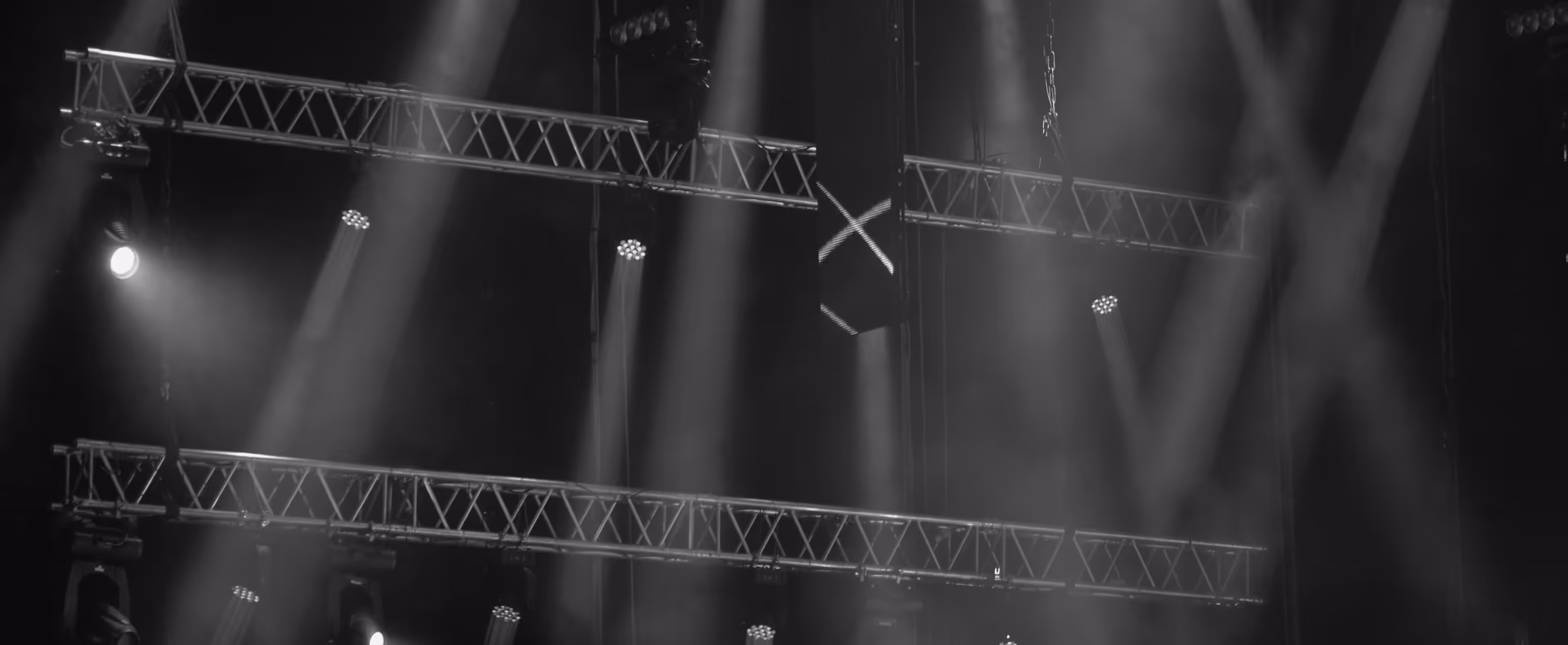 Concert stage lights shining through haze during live music event