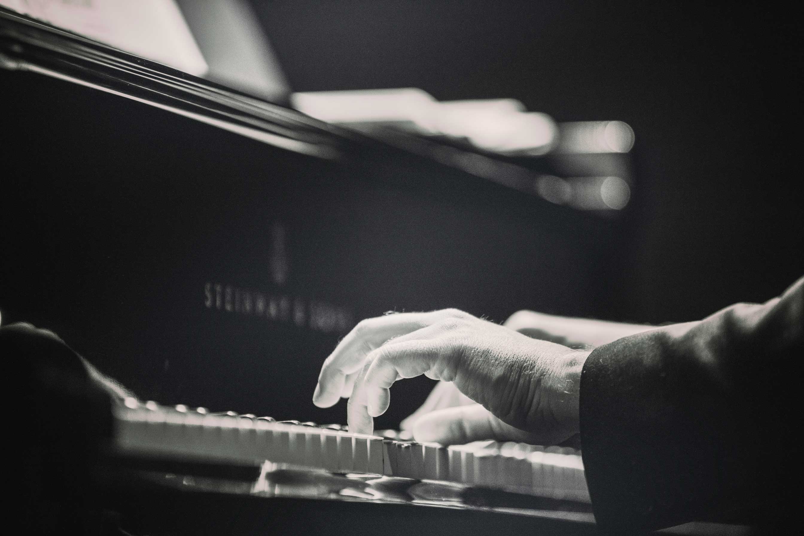 Close-up black and white image of hands playing a Steinway & Sons piano.