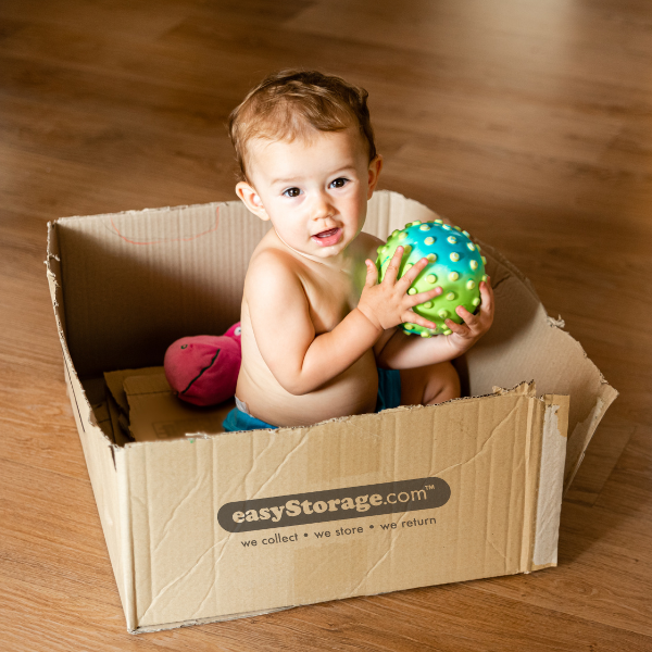 Baby holding toys in an easyStorage cardboard box