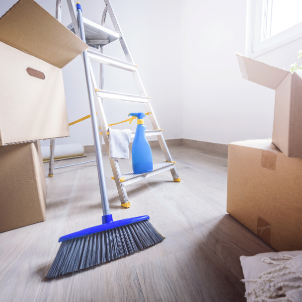 Moving boxes in new empty house with sweeping brush and cleaning supplies