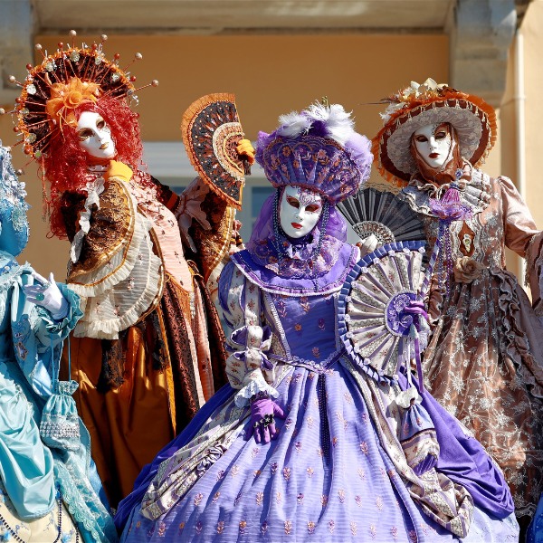 A group wearing carnival masks and old fashioned ball gown costumess