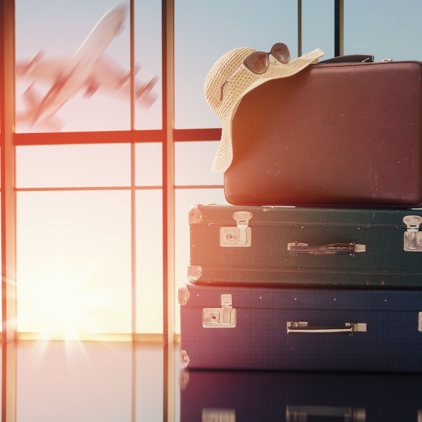 A pile of suitcases at the airport with a plane taking off in the background