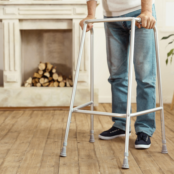 A person using a walking frame at home by a fireplace