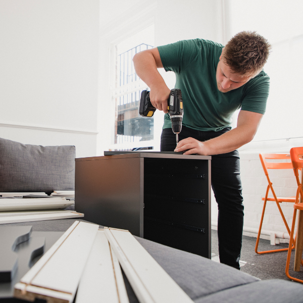 A young student building furniture in his new house share