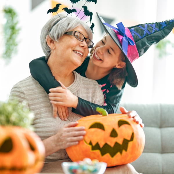 Grandmother and granddaughter decorating pumpkins for Halloween