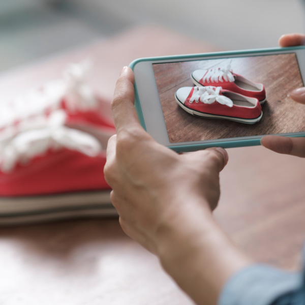 a close up of someone using a smartphone taking a photo of red and white trainers