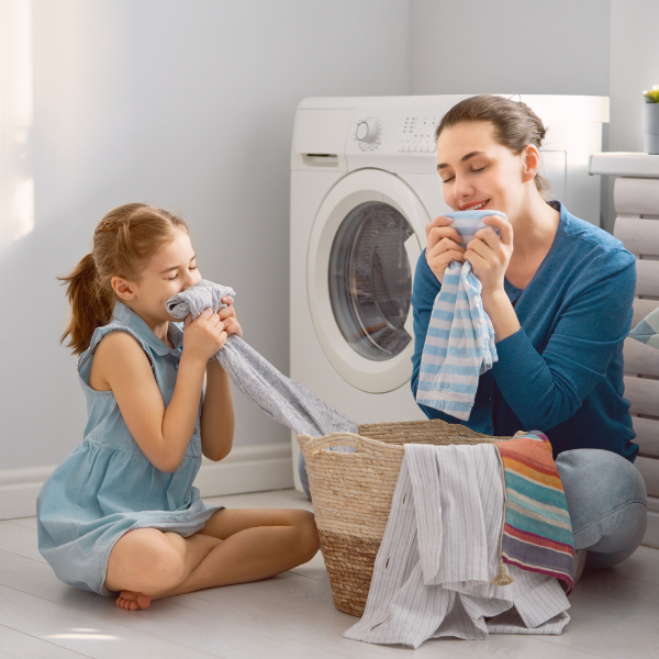 Mother and young daughter smelling clean laundry
