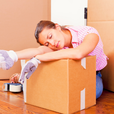Woman sleeping on a cardboard box after moving house
