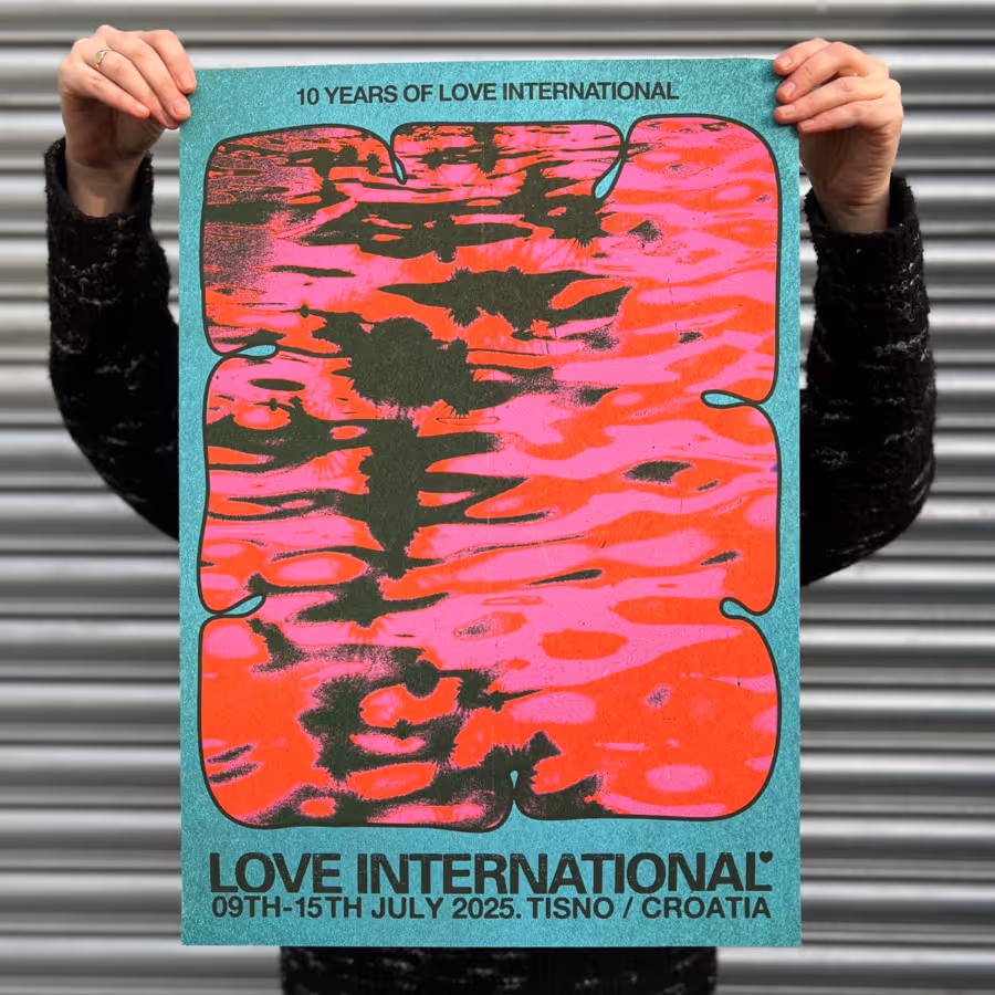 An image of a person holding up the 10 year anniversary poster for Love International 2025