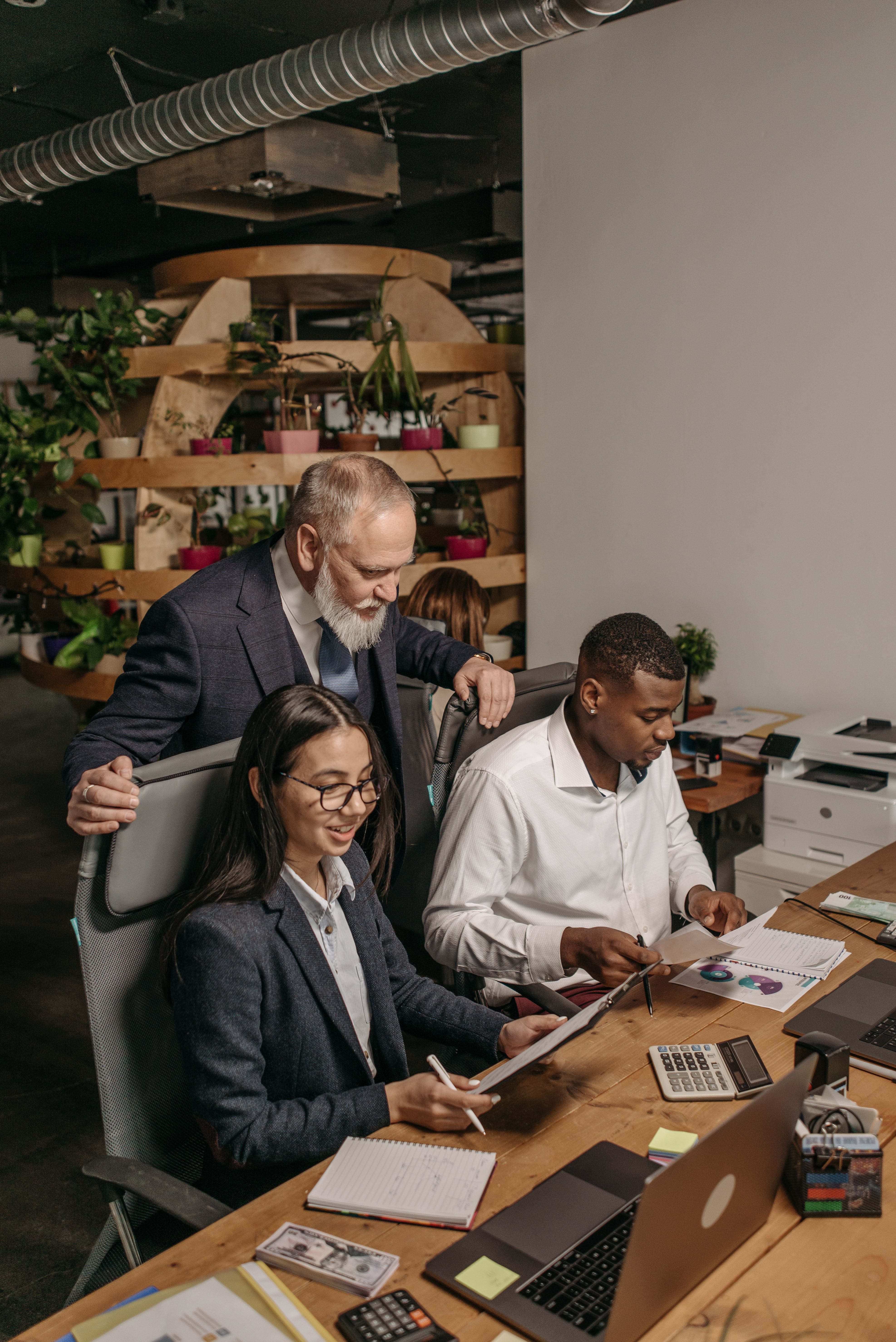 Trois personnes travaillent ensemble autour d’un bureau dans un espace de bureau moderne.