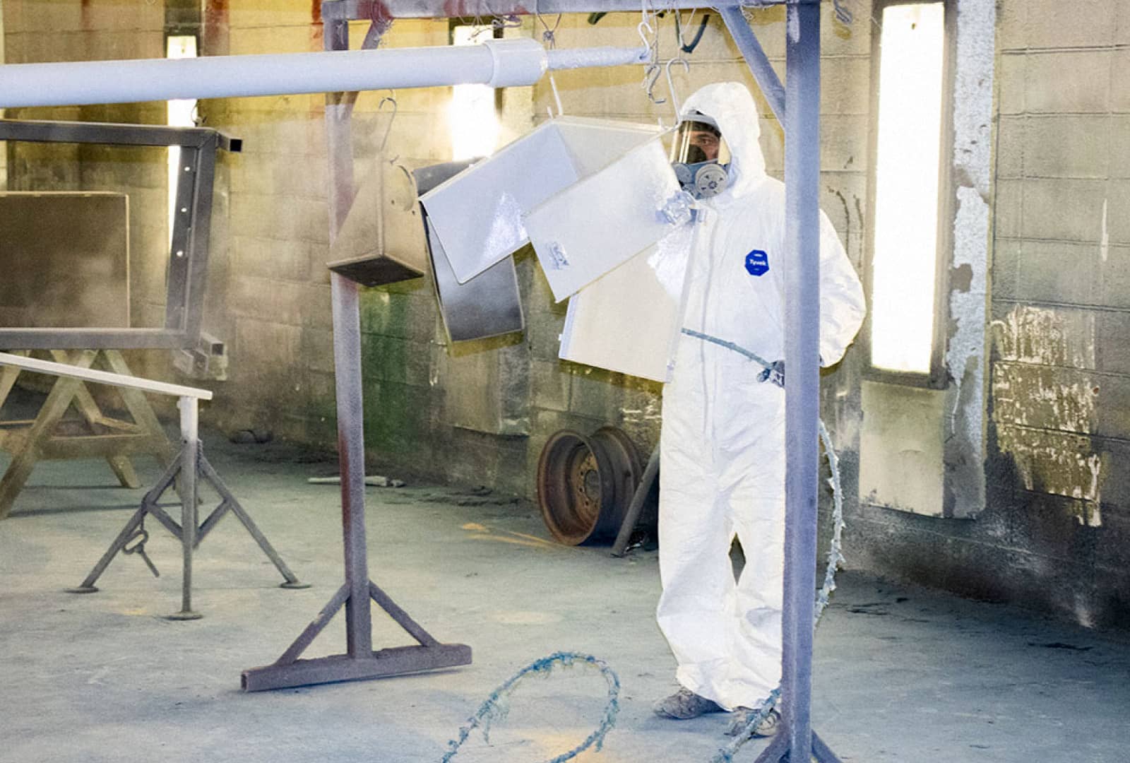 Employee in full PPE spray painting small parts