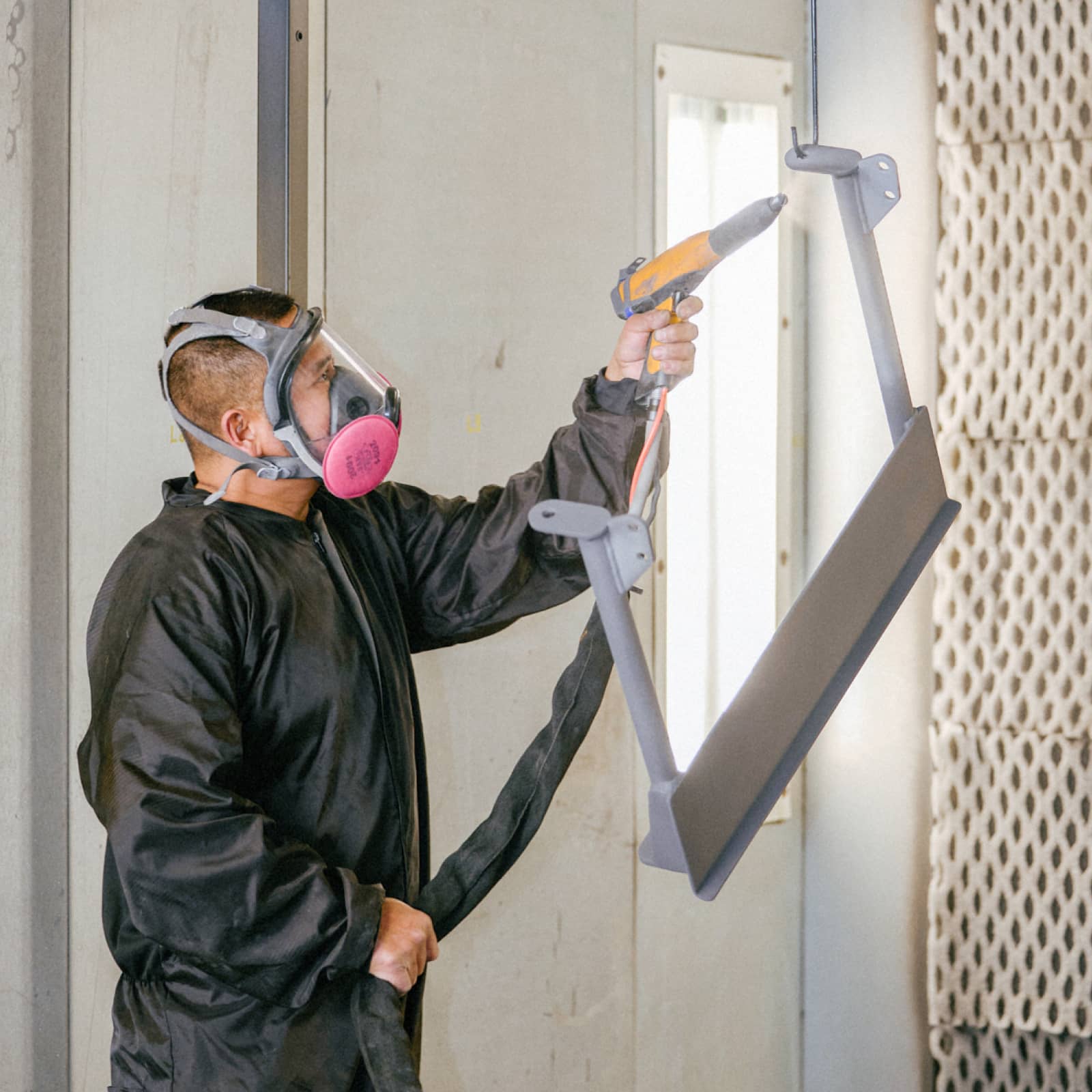 An employee spray paint coating a piece of equipment