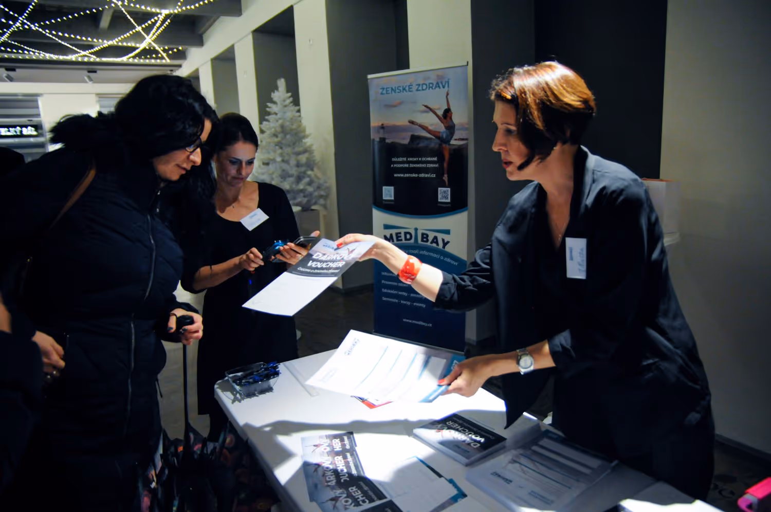 Žena dávající vzdělávací materiály návštěvnicím události