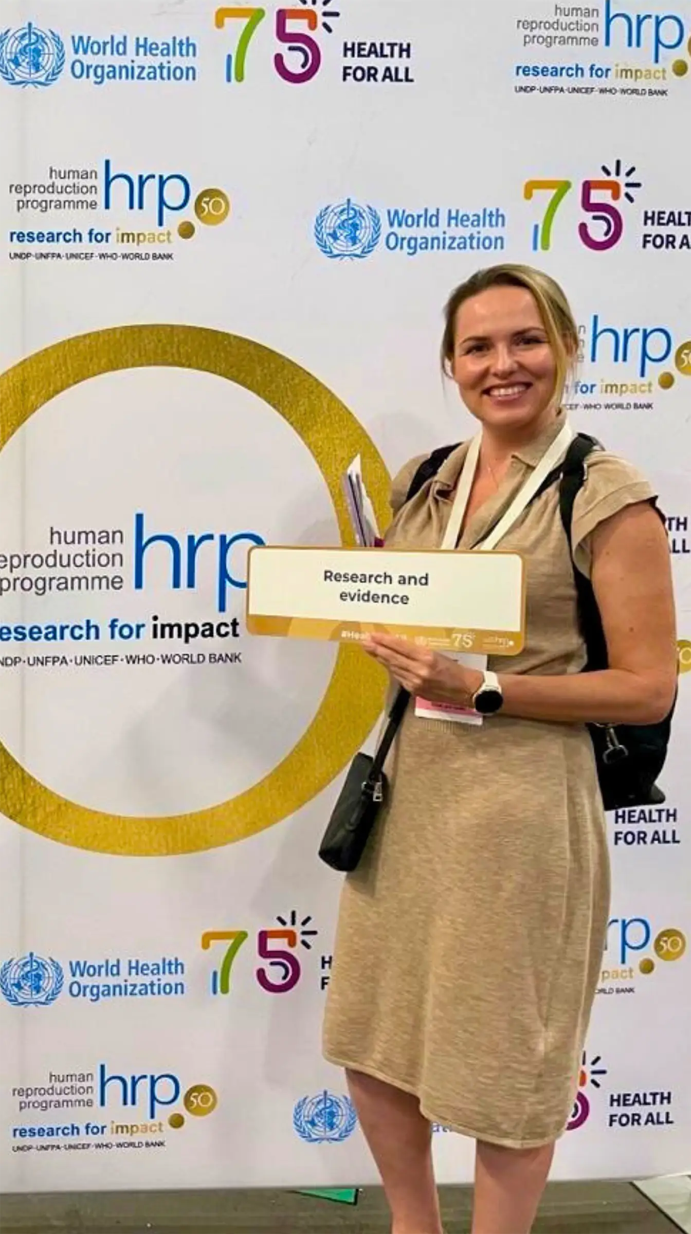 Žena stojící před reklamním bannerem.