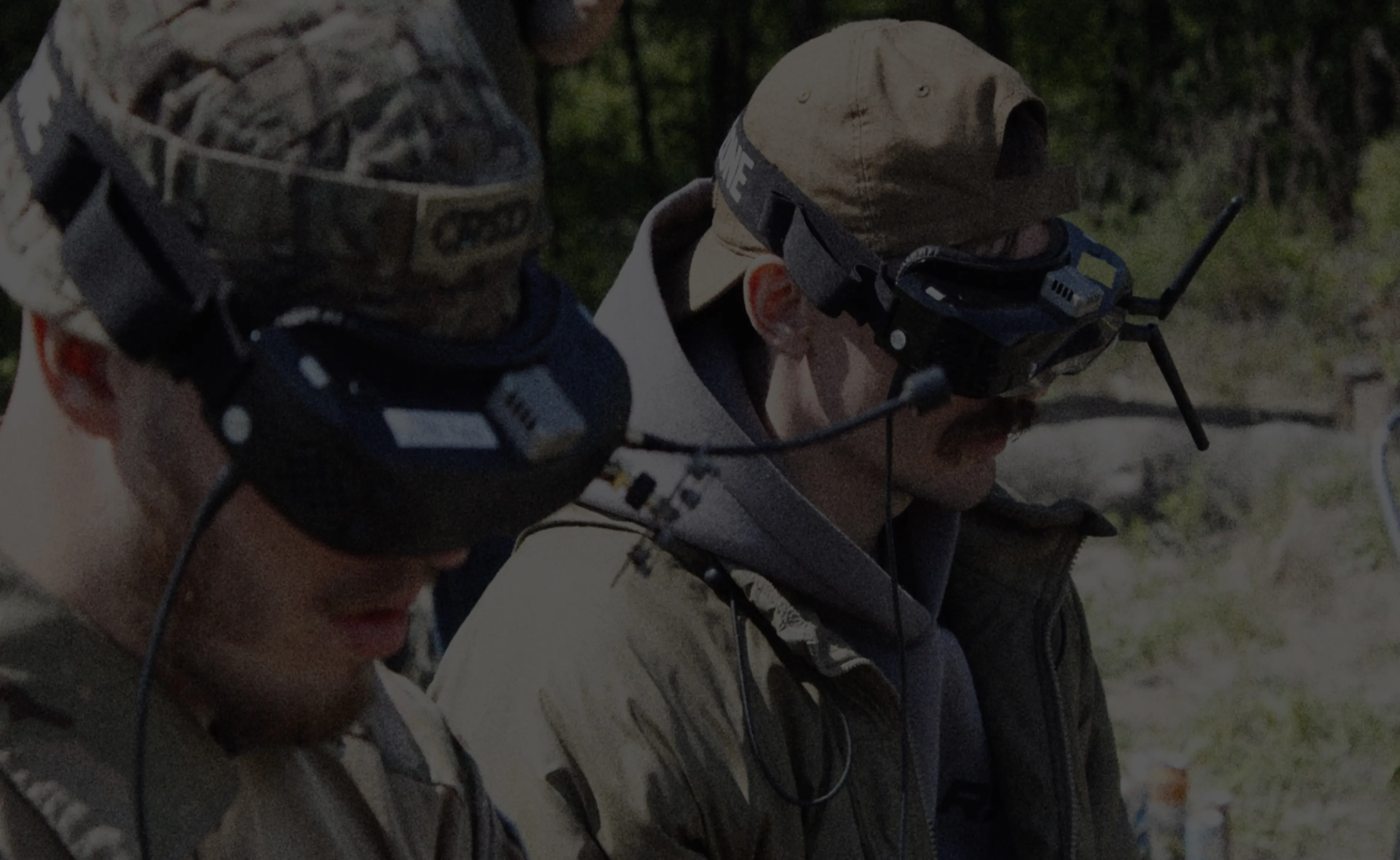 Dwóch operatorów w goglach FPV sterujących dronami podczas szkolenia na świeżym powietrzu