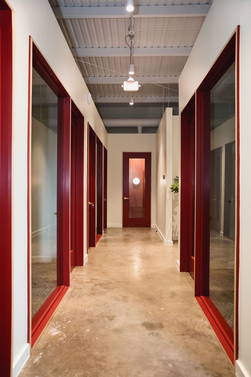 Corridor of private studios at Junto House with natural light and warm wood doors.