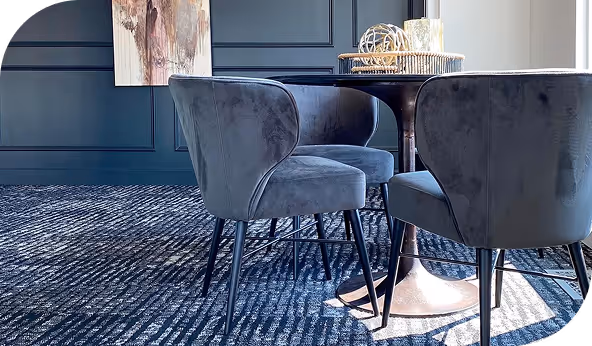 Modern dining room with dark blue carpet and velvet chairs, showcasing professional carpet installation and premium design