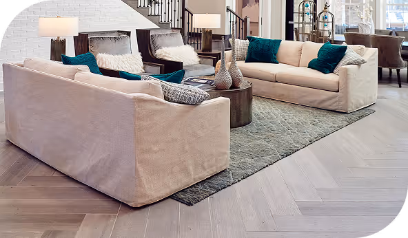 Modern living room with beige sofas, teal cushions, and herringbone vinyl flooring, highlighting versatile design options.
