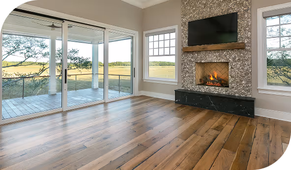 Spacious living room with hardwood flooring, large windows, and a modern fireplace overlooking a scenic outdoor view.