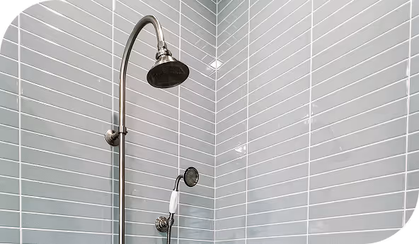 Modern shower with sleek gray tile installation and a chrome showerhead in a bathroom corner, emphasizing material quality.