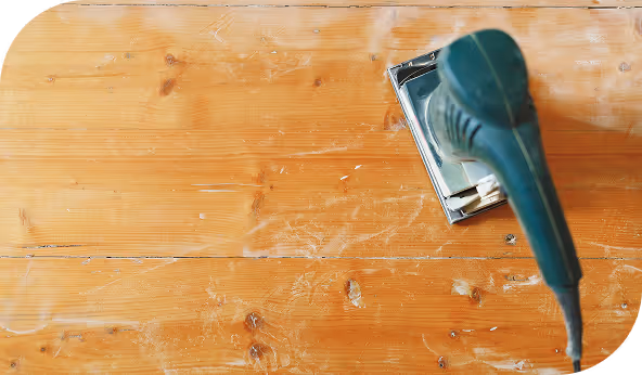 Electric sander on a wooden surface, demonstrating the refinishing process for construction projects.