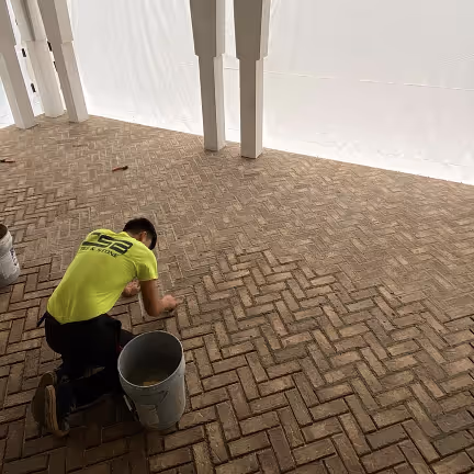 Worker installing herringbone pattern exterior tiles on a patio.