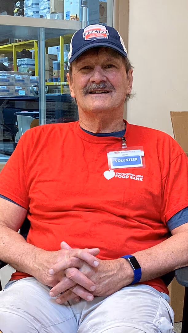 a man smiles while volunteering at the food bank warehouse