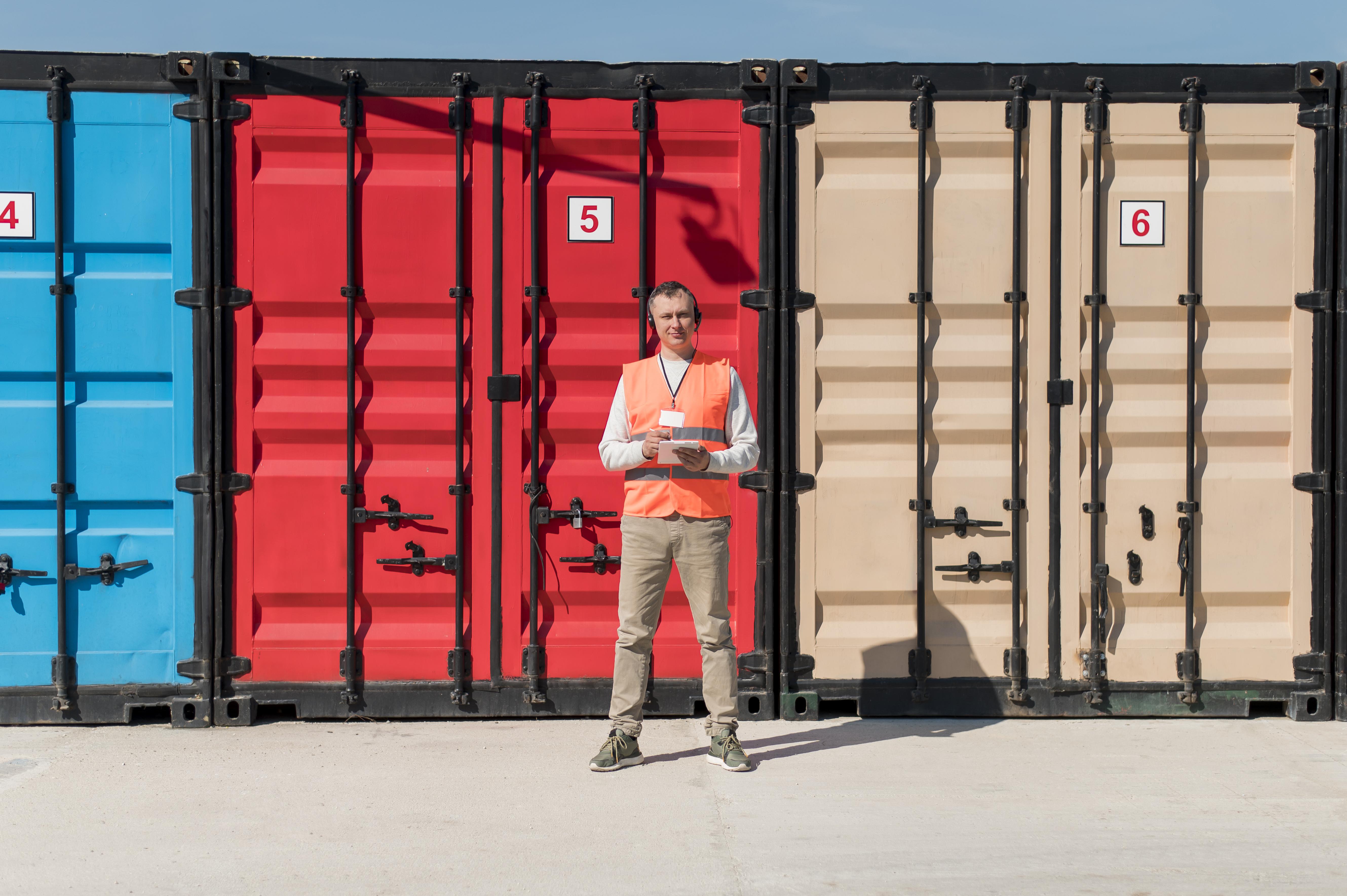 Warehouse worker in safety gear operating an electric pallet jack inside a logistics facility.