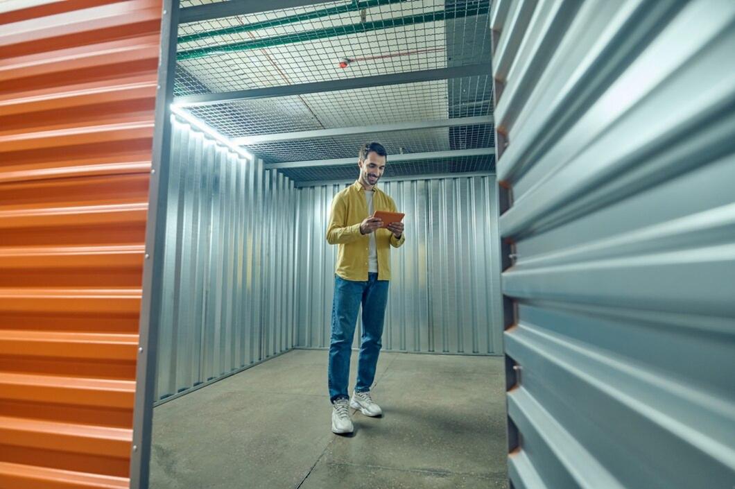 Warehouse worker in safety gear operating an electric pallet jack inside a logistics facility.