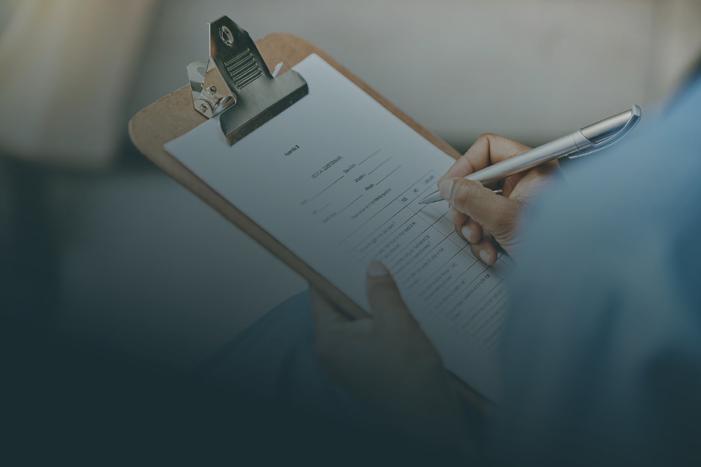 Person holding a clipboard and filling out a clinical questionnaire with a pen.