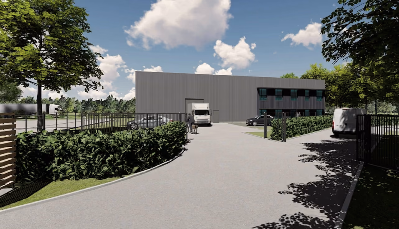 Vue extérieure d'un bâtiment industriel avec un camion blanc, voitures, arbres et ciel ensoleillé.