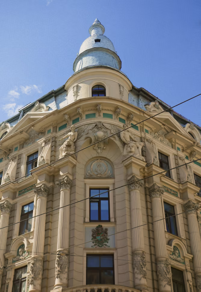 Façade ornée d'un bâtiment ancien avec toit en flèche blanche sous un ciel bleu.